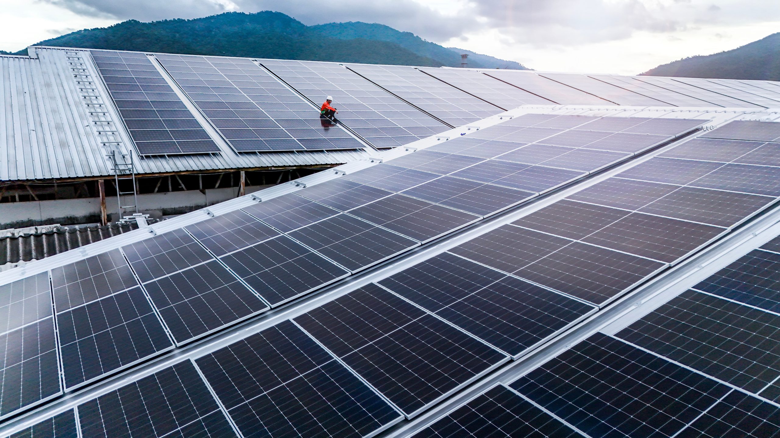 Technician,Installs,A,Large,Photovoltaic,System,On,An,Industrial,Rooftop.